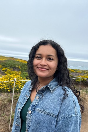 Anika smiling in front of flowers near oceanview